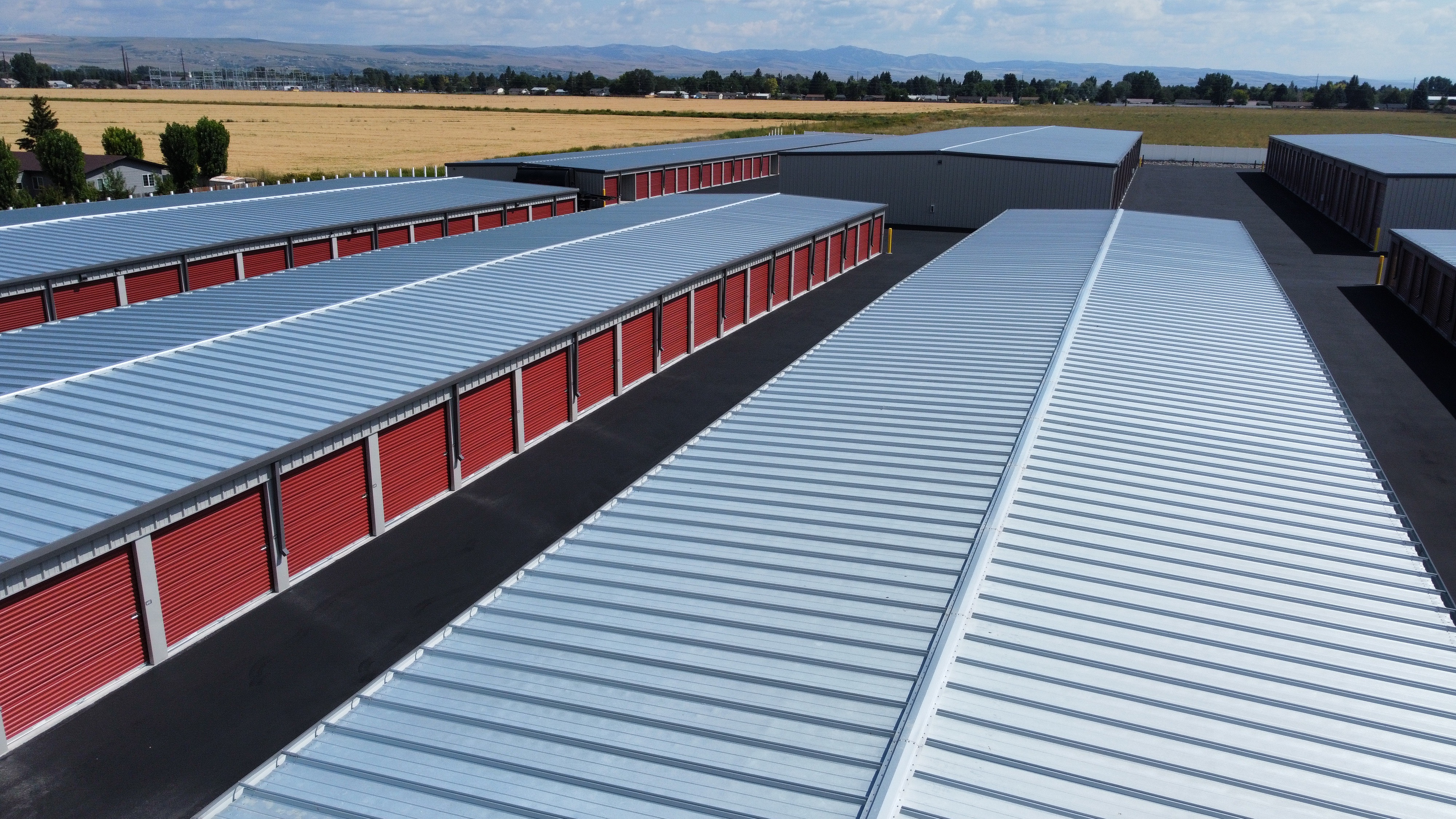 Drone aerial view of storage facility with red roll-up doors and freshly sealed asphalt by JCPM